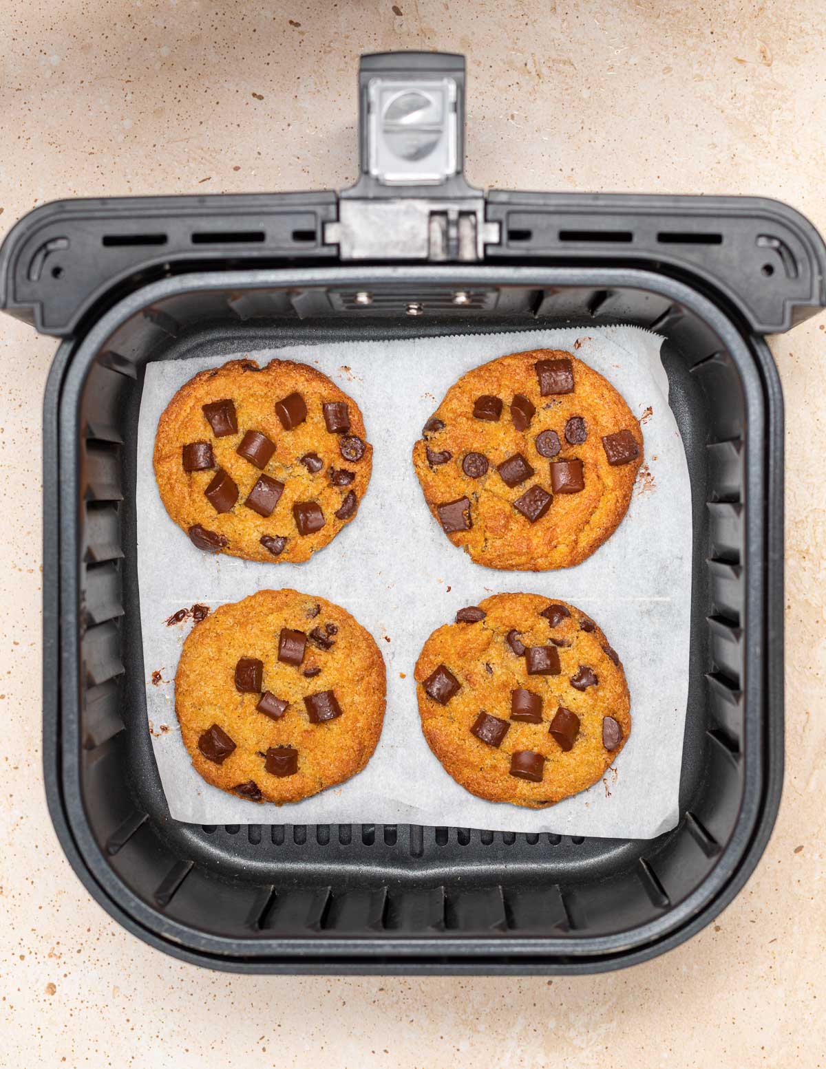 4 cooked cookies in an air fryer basket