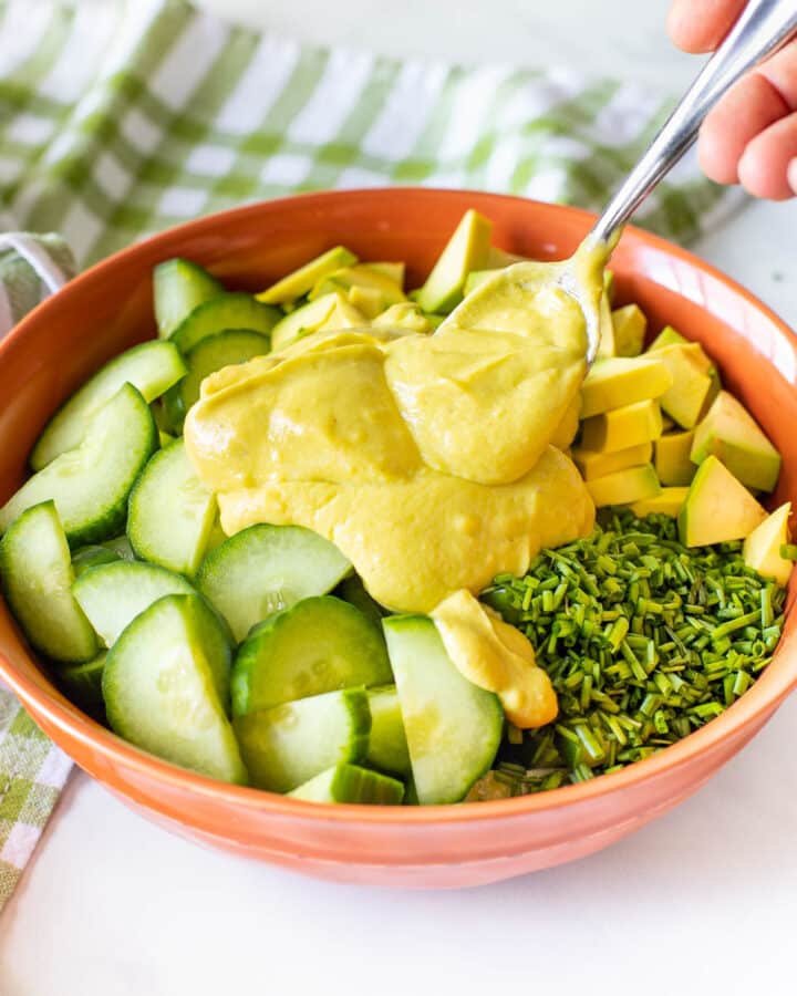 vegan avocado dressing being spooned onto a salad