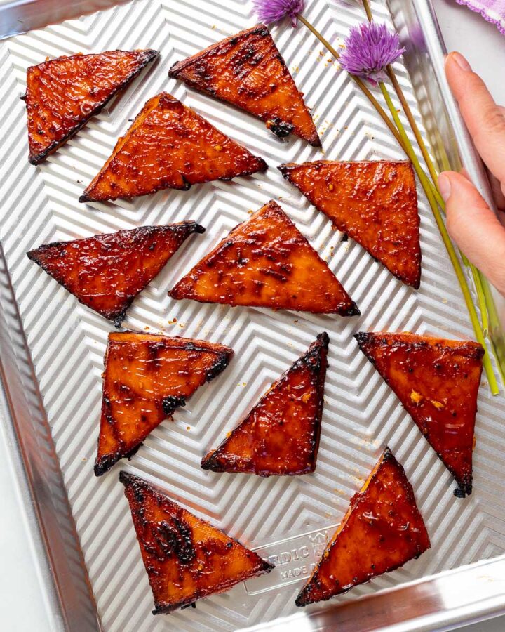 a baking tray with triangles of baked tofu and a couple of pretty chive flours
