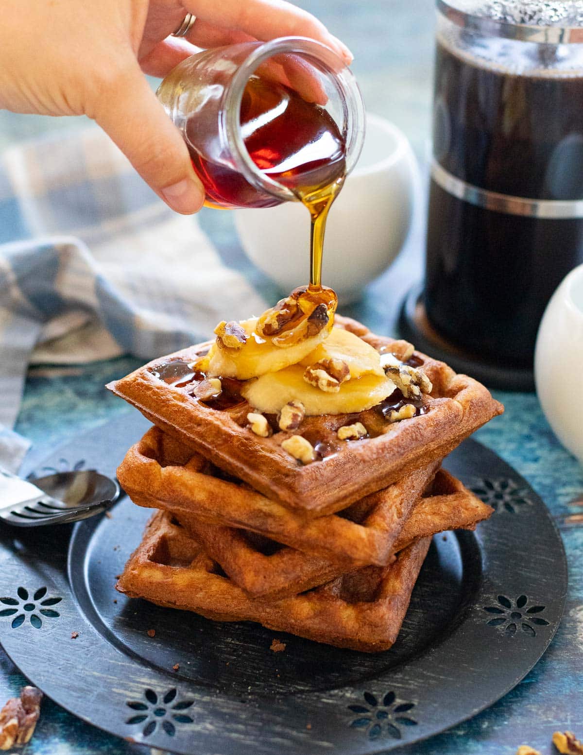 maple syrup pouring over a stack of vegan banana waffles