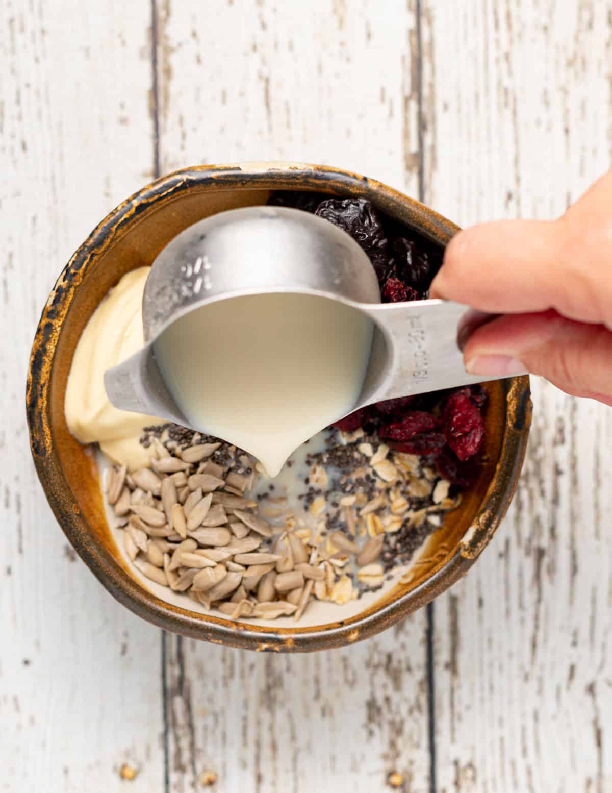 plant milk pouring into a bowl of oat, fruit and yogurt