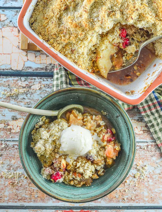 Overhead shot of Cranberry Apple PearVegan Crumble served up in a bowl with casserole full of crumble next to it