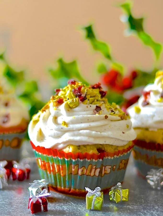 Festive, fragrant & delicious pistachio cranberry orange muffins! Orange scented, studded with juicy, jewel red cranberries & crunchy, vibrantly green pistachios & finished with a swirl of vanilla cream.