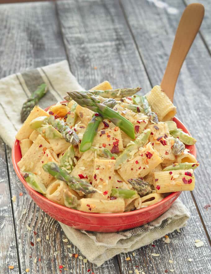 Creamy Asparagus Lemon Vegan Pasta Salad in a red bowl on a rustic wood backdrop
