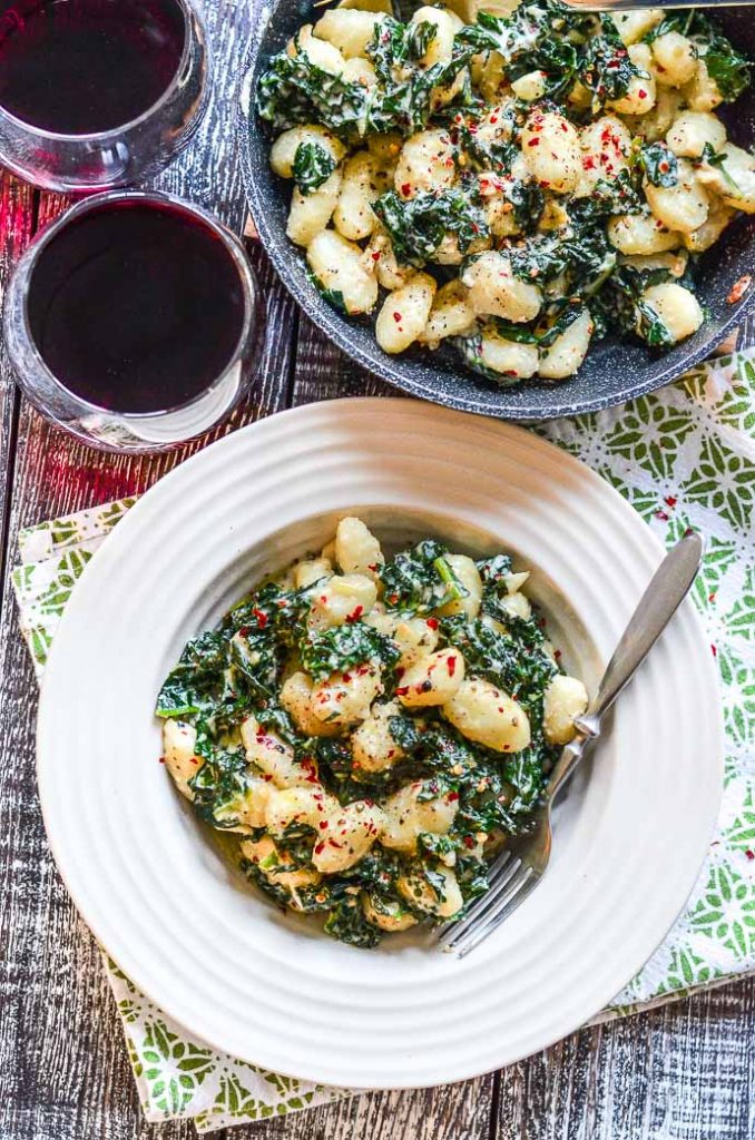 Vegan Gnocchi in a bowl with 2 glasses of wine and the pan the gnocchi was cooked in, all take from above