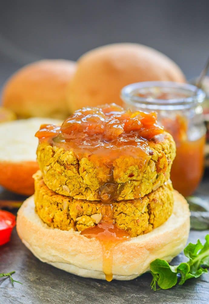 curried chickpea burgers stacked on a bun with a dribble of mango chutney running down the side
