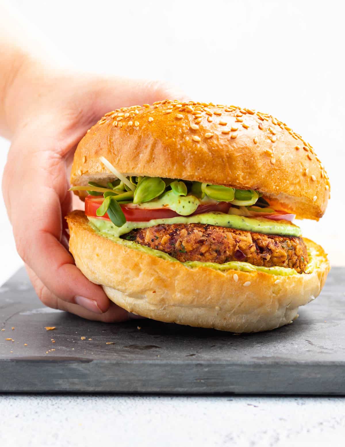 a hand holding a burger in a bun