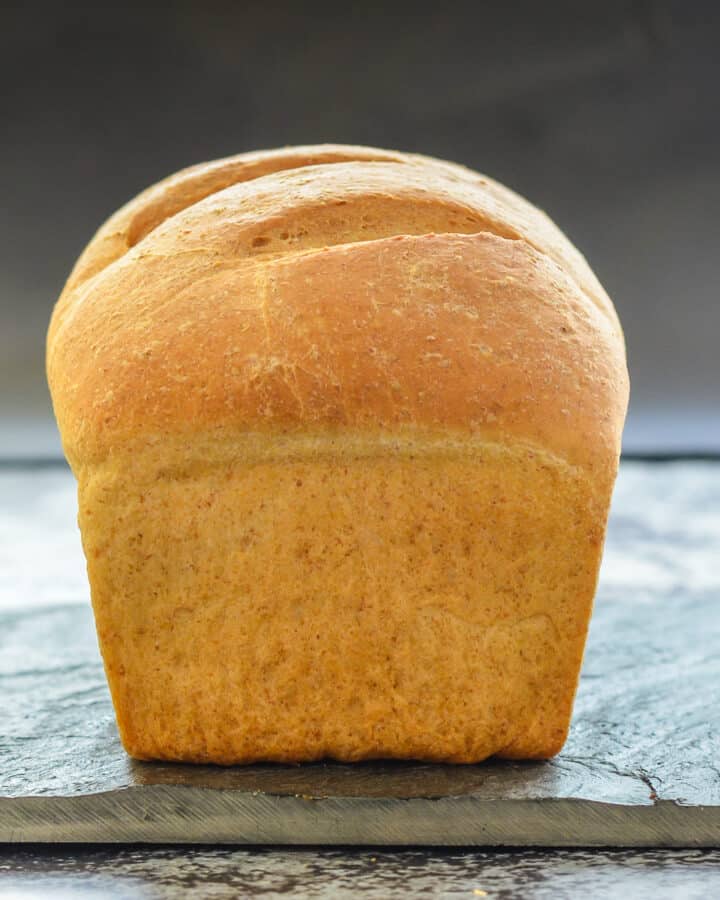 an uncut loaf of crusty bread on a slate board