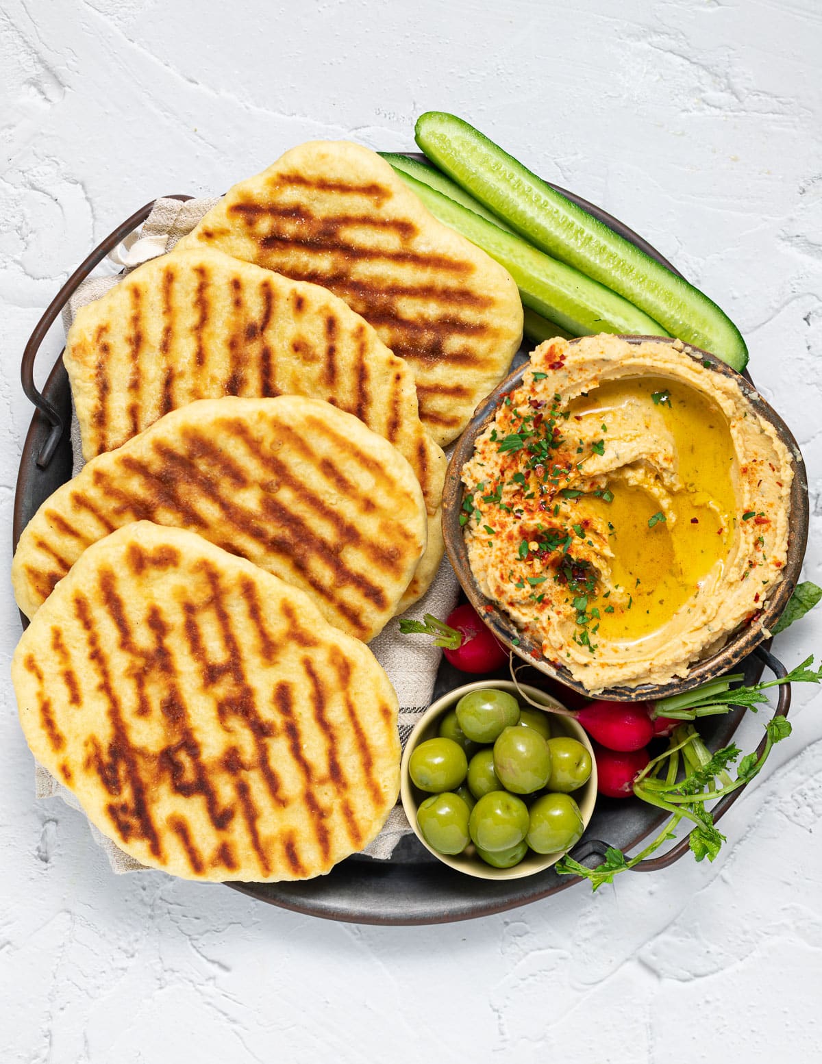 a platter with flatbreads, hummus and veggies 