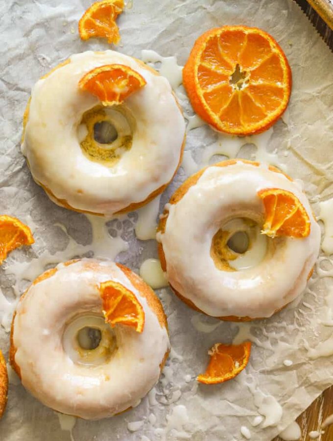 3 frosted, sticky, orange olive oil baked donuts with candied orange pieces