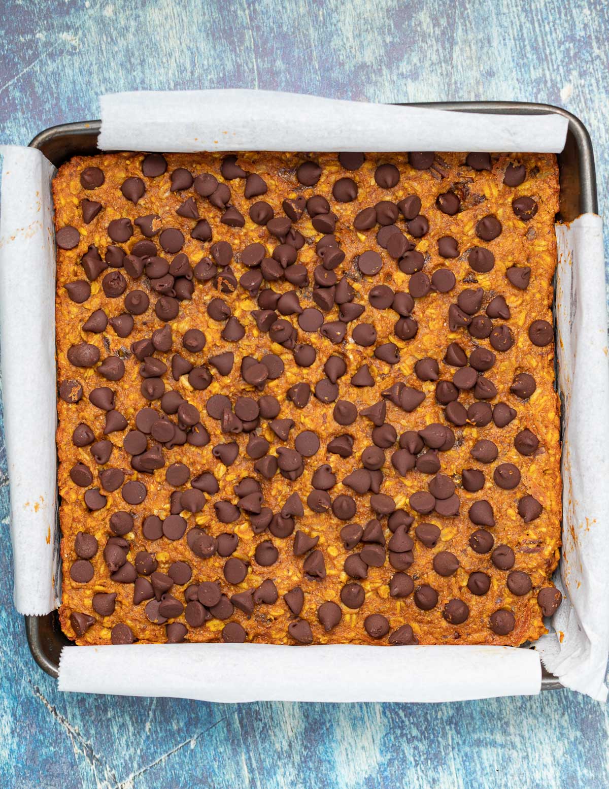 a pan of uncut oatmeal bars with chocolate chips on top