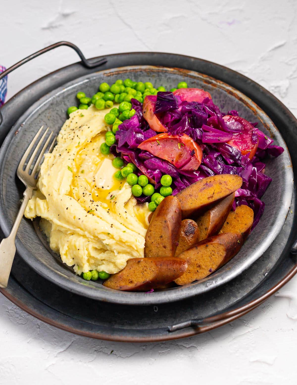 red cabbage, mashed potato and sausages on a metal plate