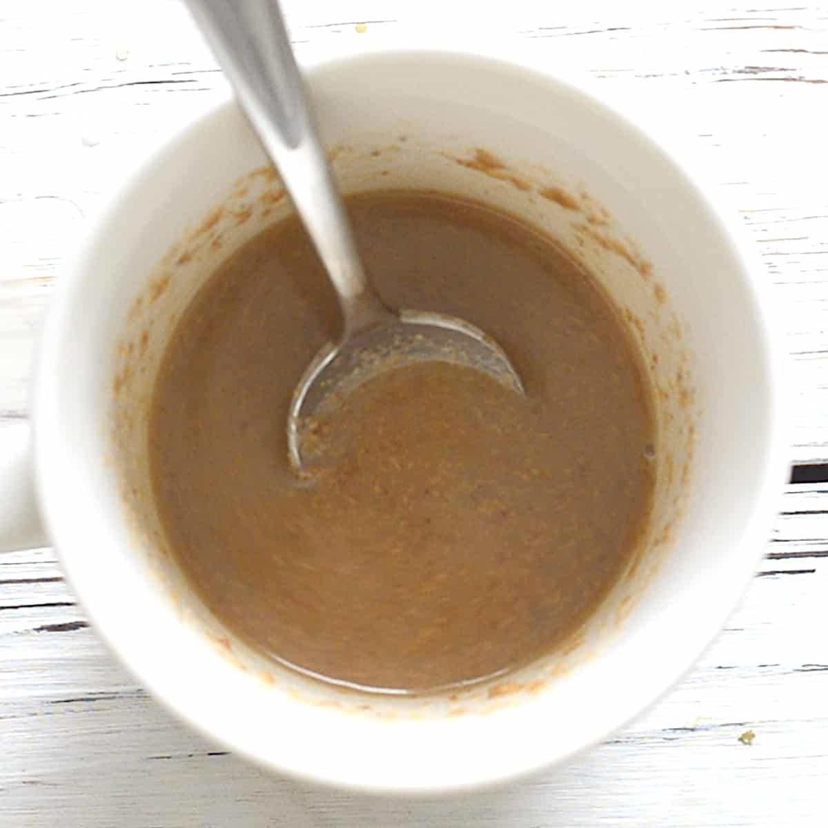a mug with nut butter, plant milk and vanilla mixed up in it 