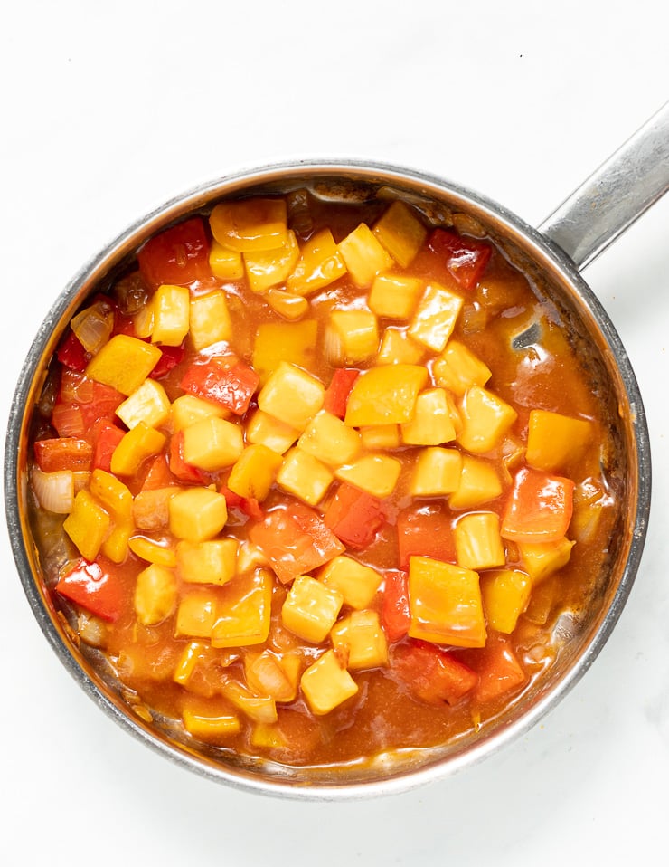 sweet and sour sauce with bell peppers and pineapple chunks in a pan