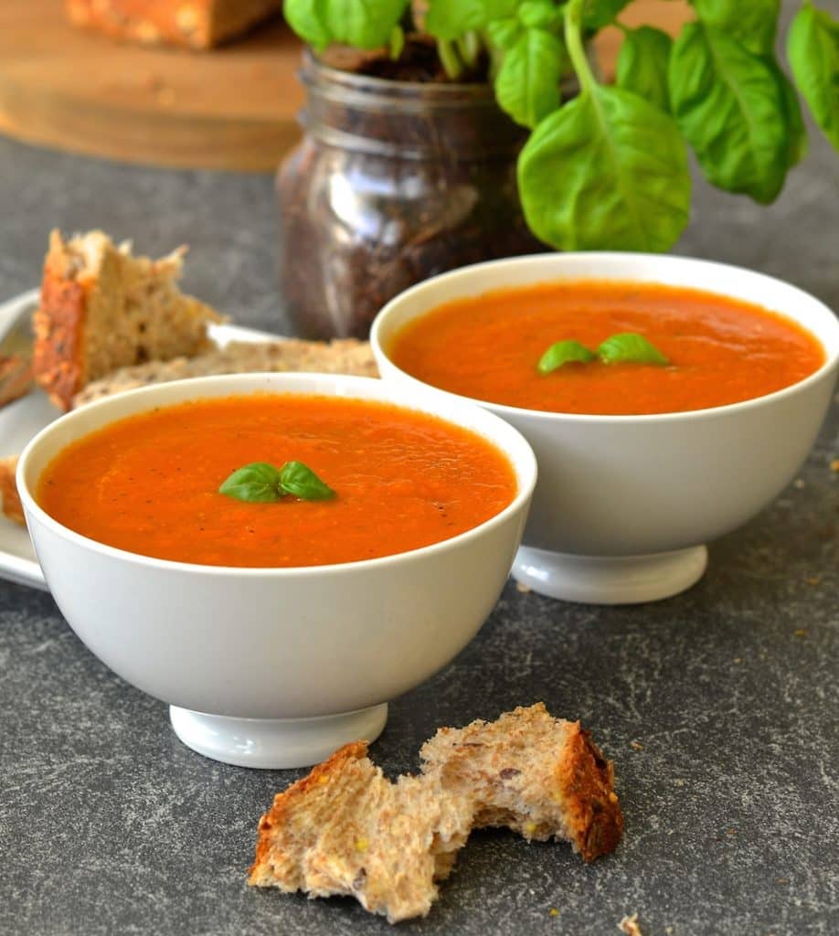 easy tomato basil soup in bowls with chunks of bread strewn around