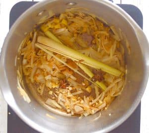 onions, garlic, lemon grass, cinnamon & star anise in a pan - making udon noodle soup