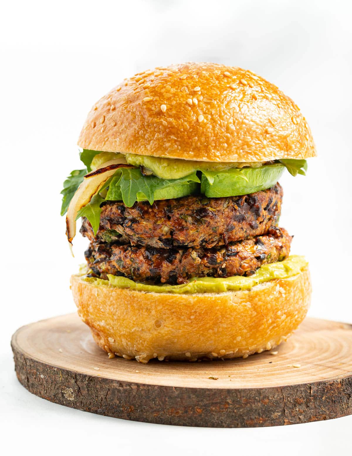 a double black bean burger stack in a bun with lettuce and avocado