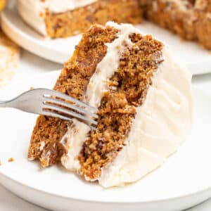 a slice of frosted vegan carrot cake on a plate