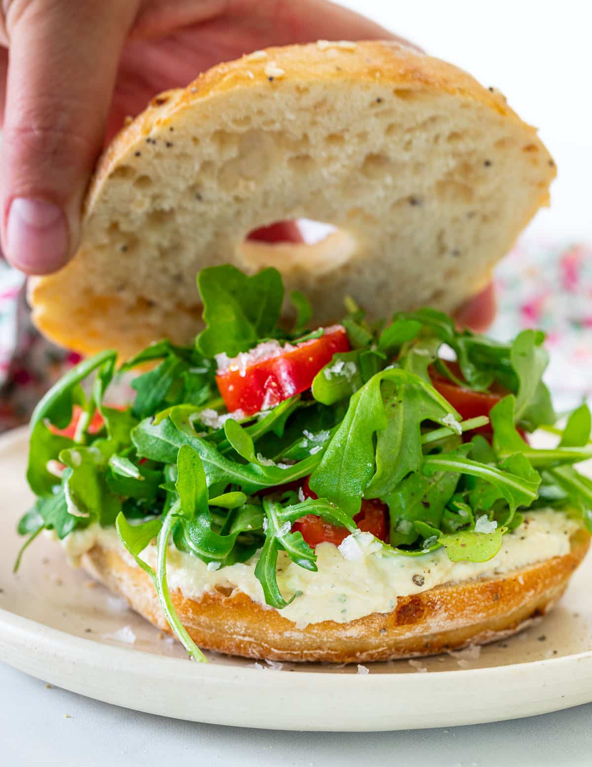 a bagel filled with vegan cream cheese, arugula and tomato