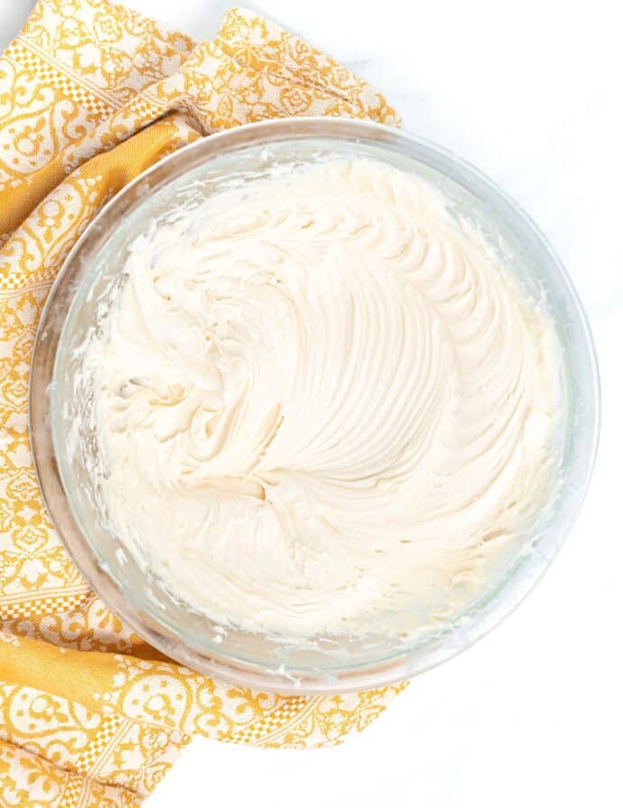 a bowl of vegan cream cheese frosting with pretty patterns from the whisk