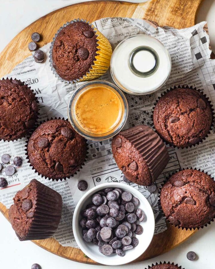 muffins on a wooden board with a bottle of plant milk, espresso and chocolate chips