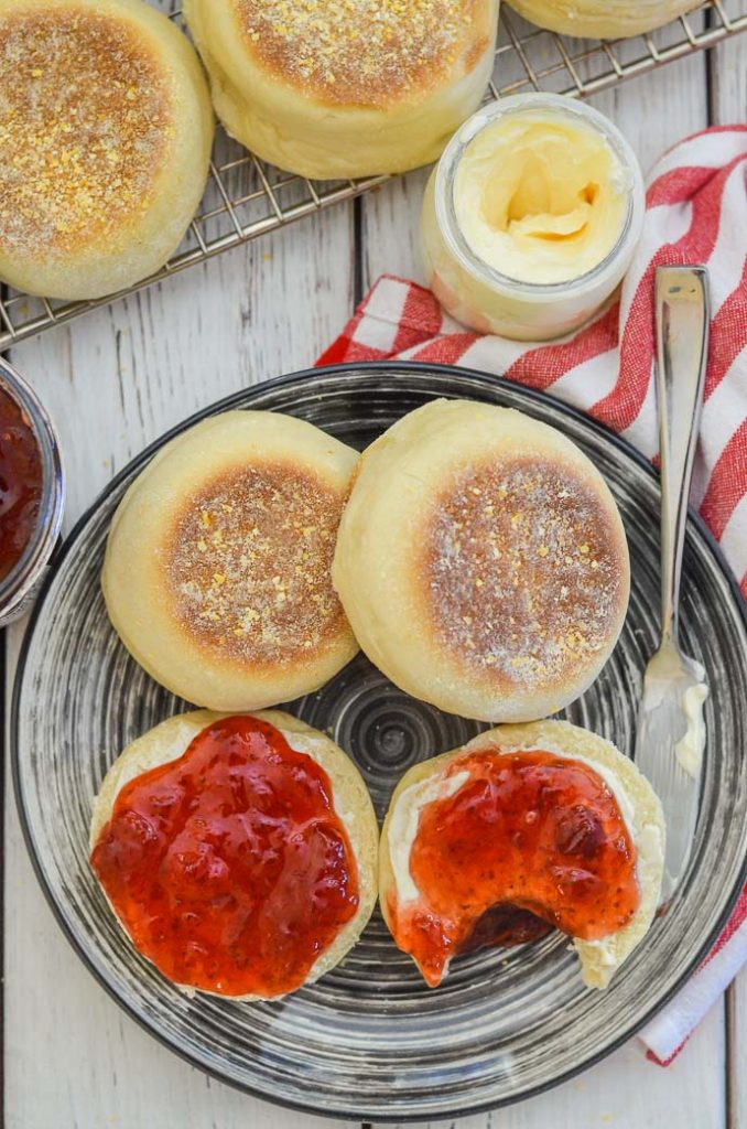 Homemade English Muffins from above. One a plate with butter and jam.