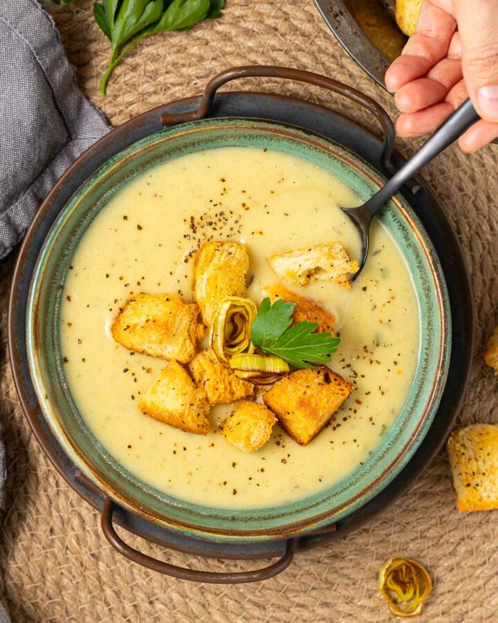 a bowl of vegan leek and potato soup with croutons