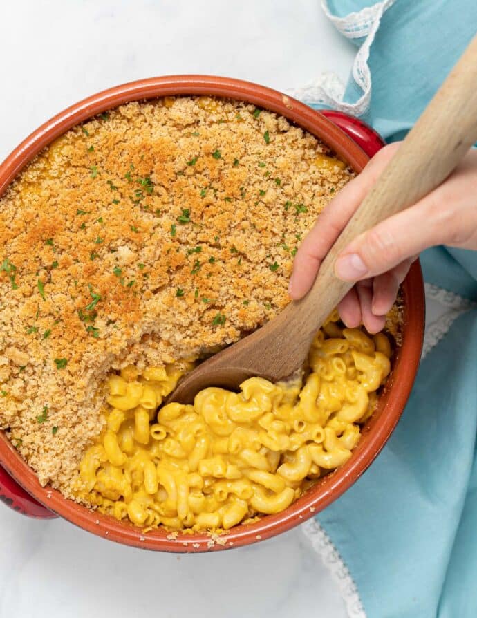 a spoon taking a portion of vegan mac and cheese from a dish