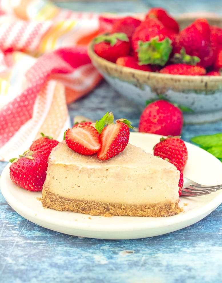 a slice of Vegan New York Cheesecake on a plate with strawberries
