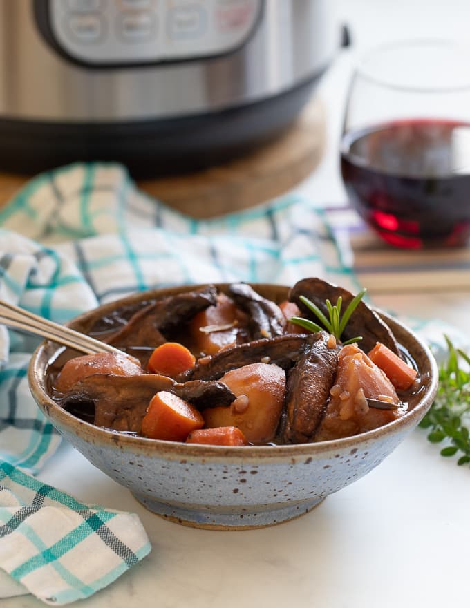 Vegan Instant Pot Portobello Pot Roast in a bowl with an Instant Pot and glass of red wine in the background