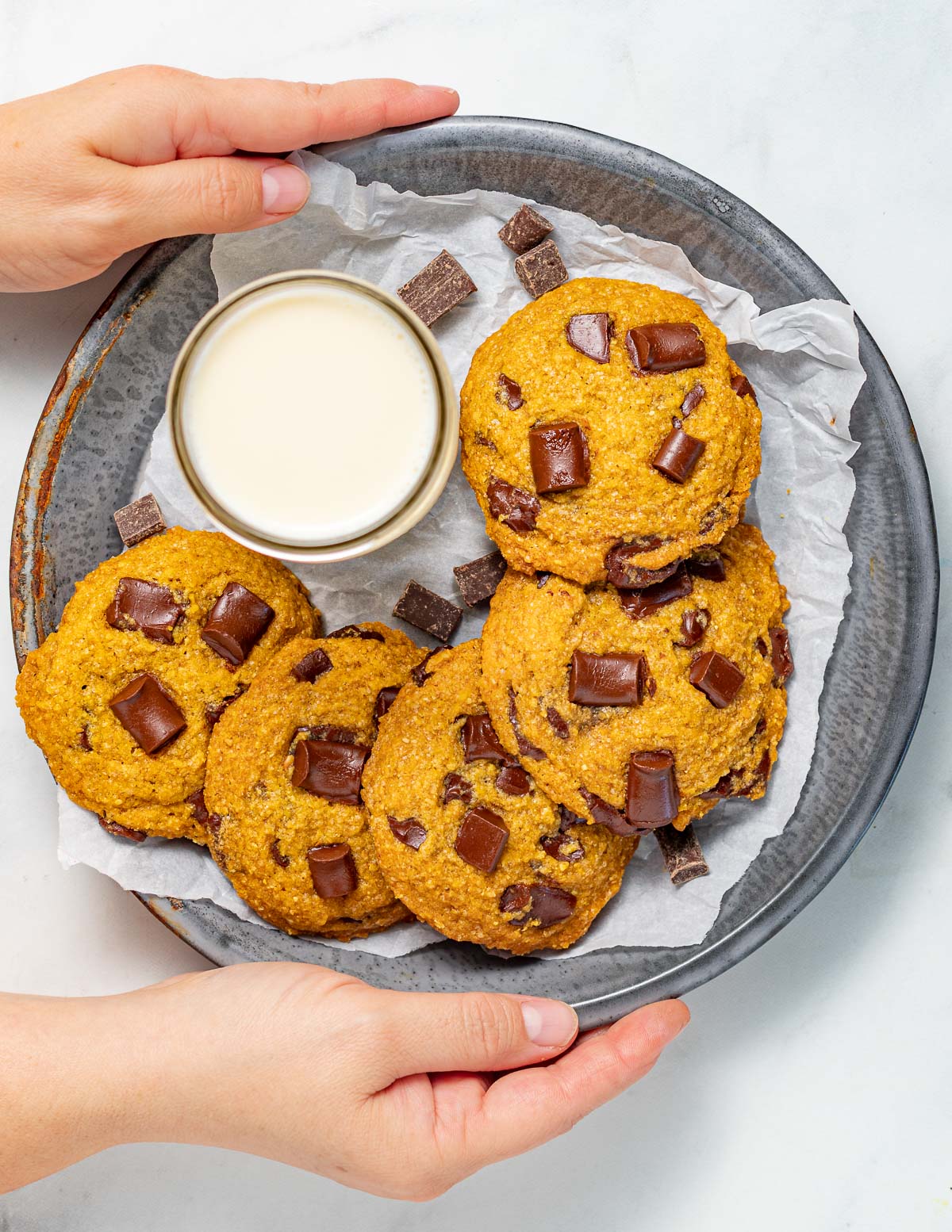 vegan pumpkin chocolate chip cookies on a tray with a glass of soy milk