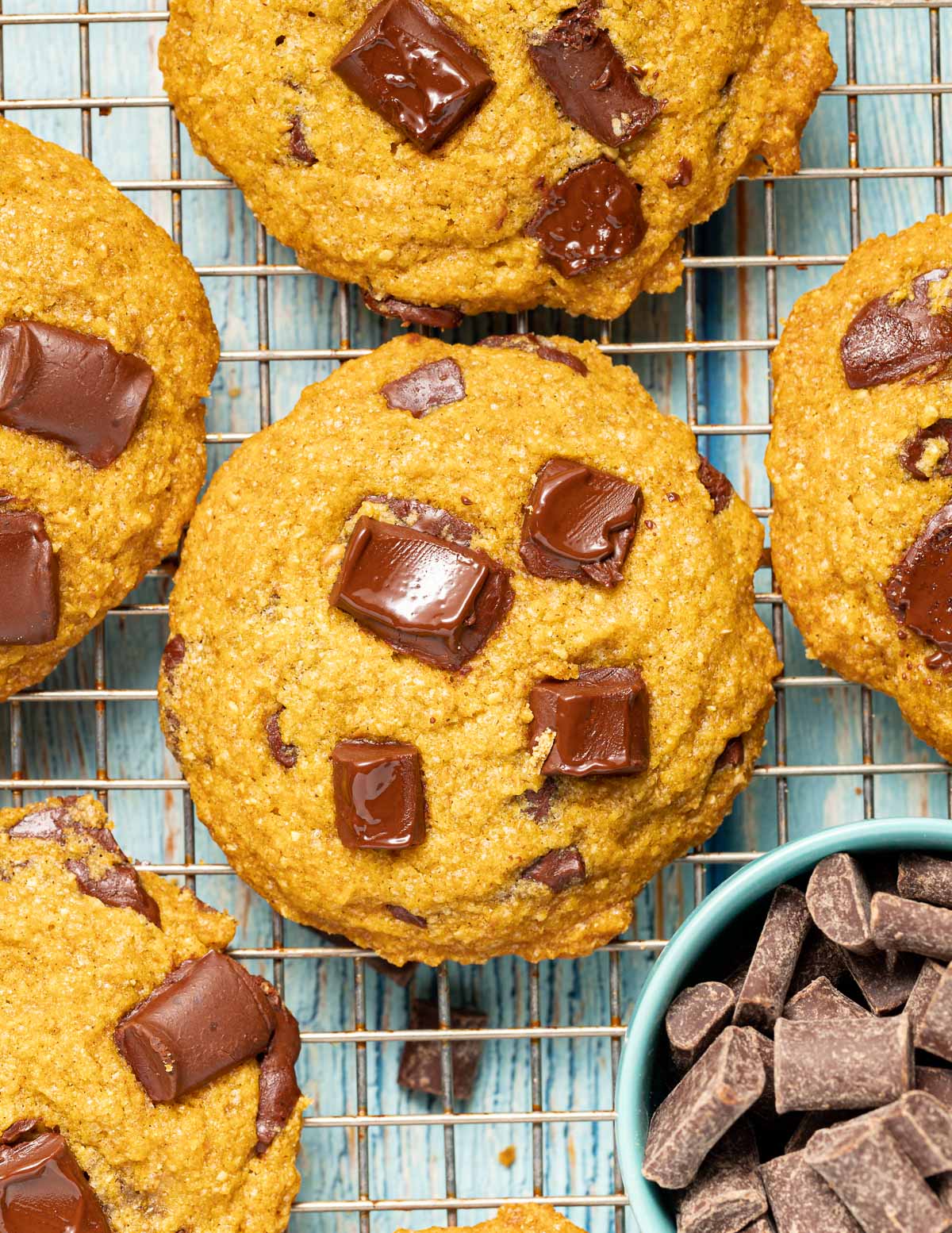 cookies on a cooling rack with a bowl of chocolate chunks