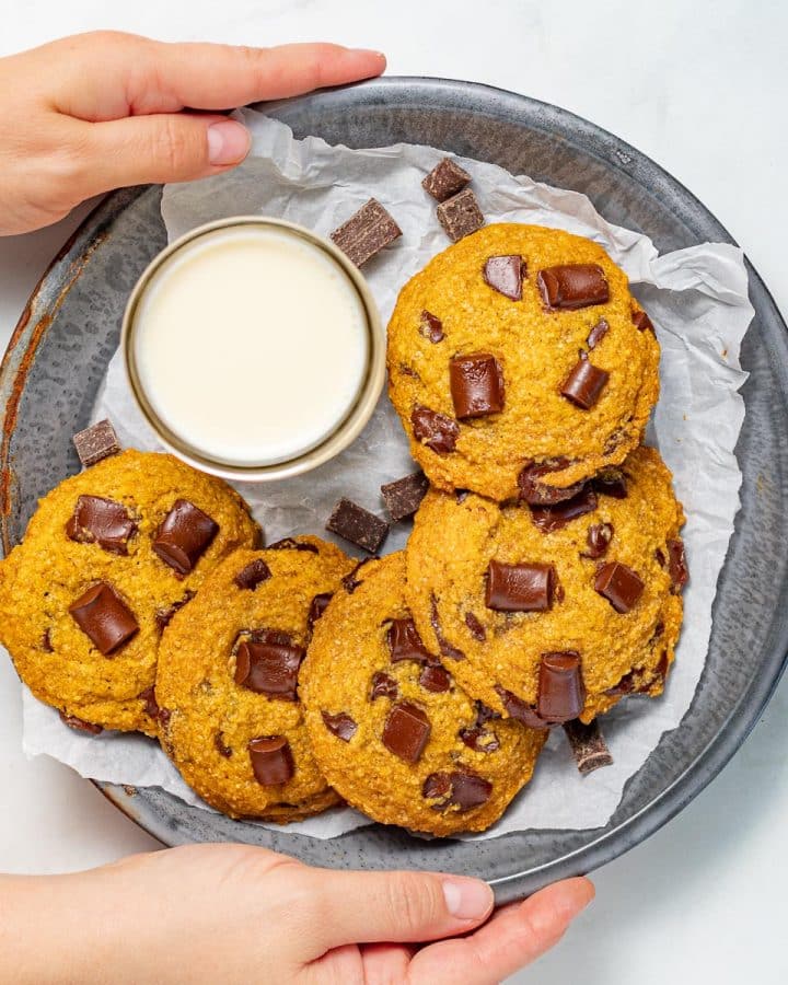 vegan pumpkin chocolate chip cookies on a tray with a glass of milk
