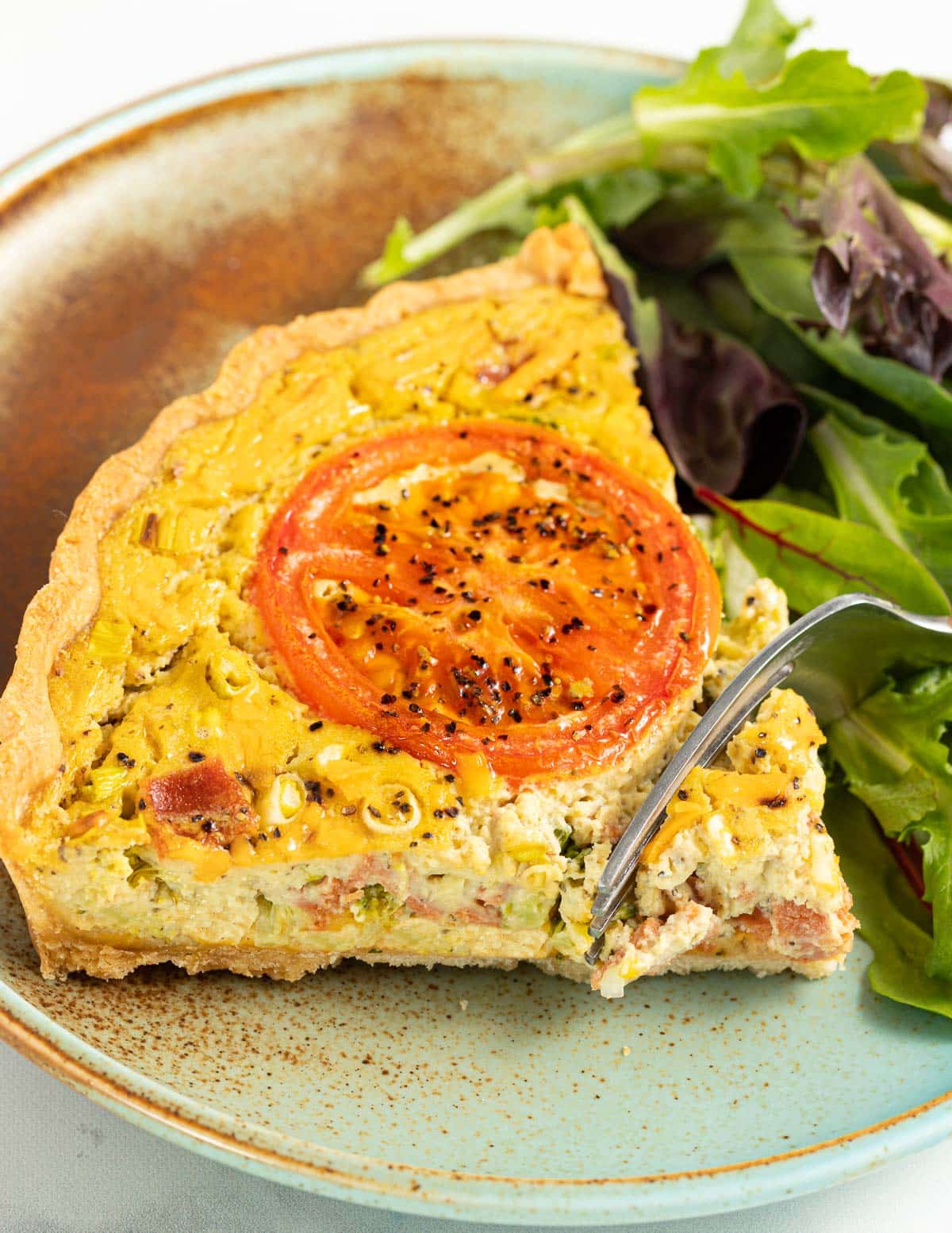 a fork cutting into a piece of quiche 