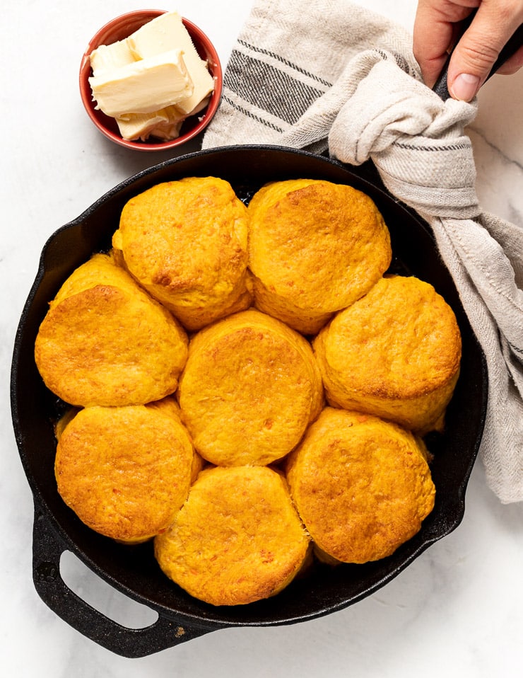 hot cooked vegan sweet potato biscuits in a cast iron skillet next to a bowl