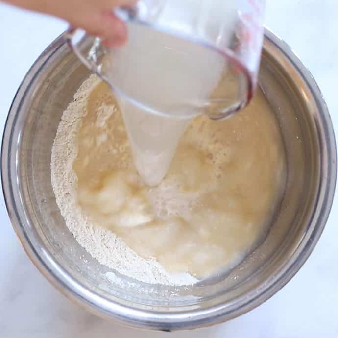 Pouring wet ingredients into dry ingredients when making Yorkshire Puddings. 
