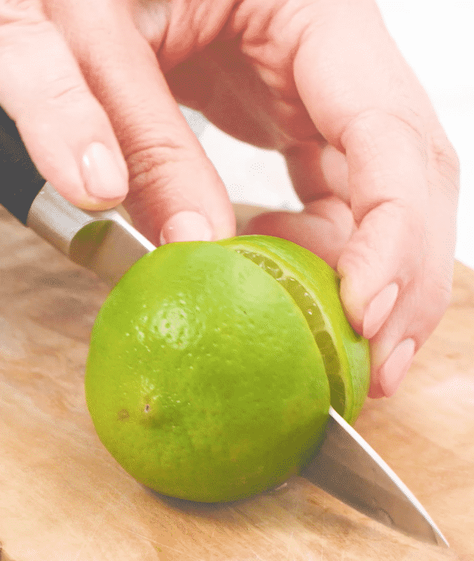 a lime being cut in half on a wooden board